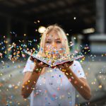 Woman blowing confetti off a book